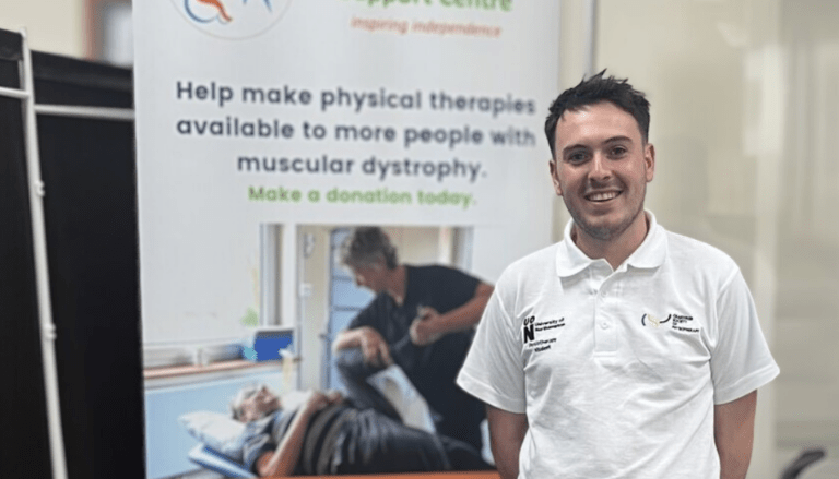 Adam is standing in our clinic in front of a MDSC pop-up banner.