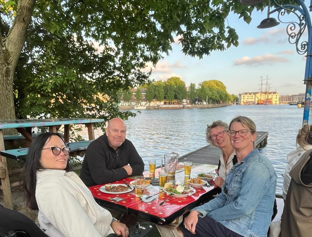 Chair of Trustees, Ruth Hereford, Trustee Roger Flemming, with Lynn and Ulrike. They are having dinner and drinks overlooking a canal.