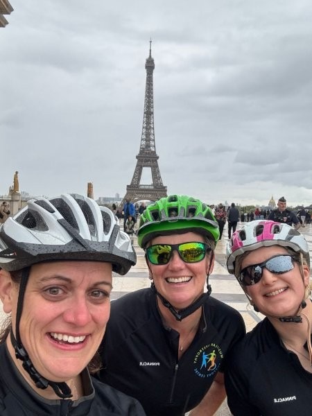 Three people in front of the Eiffel Tower smiling at the camera