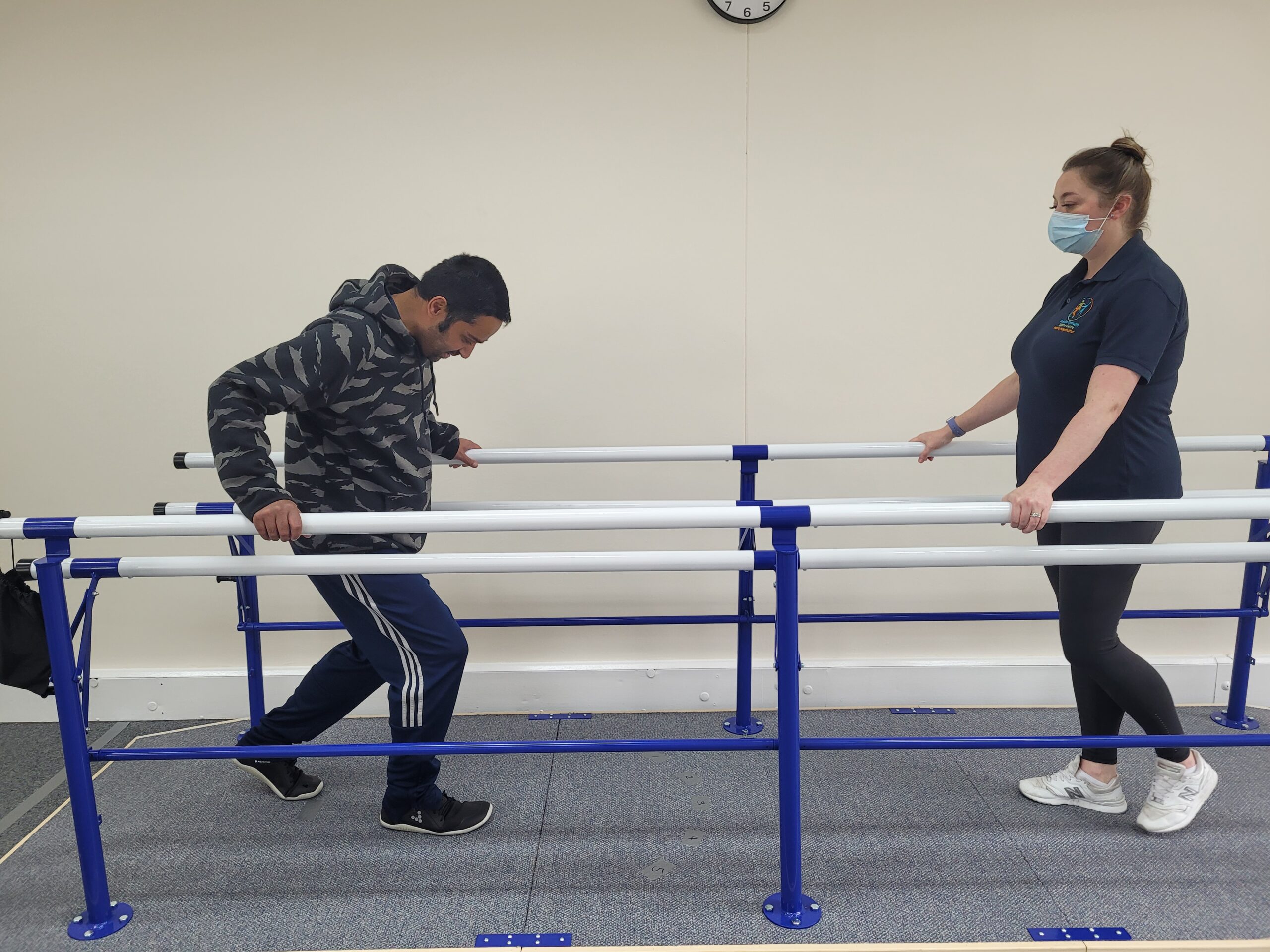 A man using the parallel bars to support himself while walking