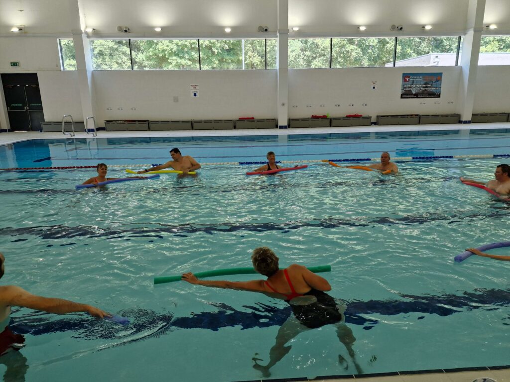 A group of people taking part in an aquatic exercise class led by a physiotherapist