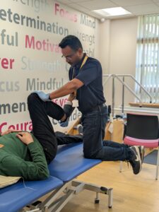 A physiotherapist kneeling on a bed treating a patient