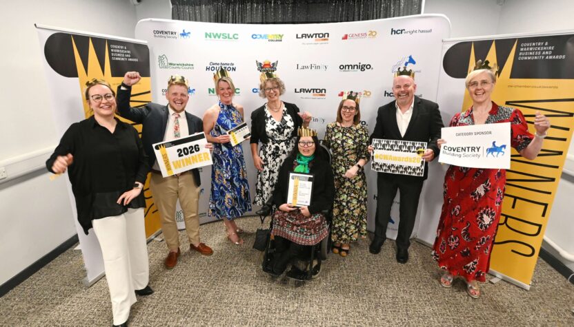 Group of award winners standing in front of Coventry & Warwickshire Business and Community Awards banners, holding certificates and “2026 Winner” signs, with sponsor logos visible behind them.