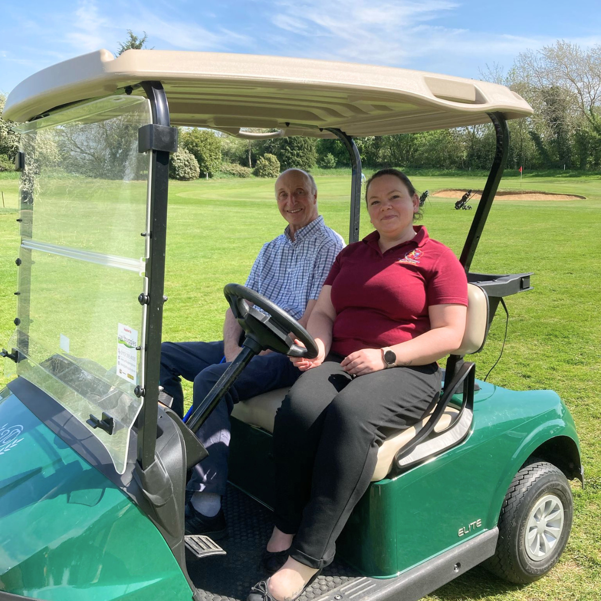 Two people sitting in a golf cart.
