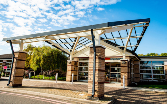 Brick building entrance to MD Support Centre Coventry with yellow-framed glass doors, signage displaying unit numbers 9 and 10, and a banner beside the doorway.