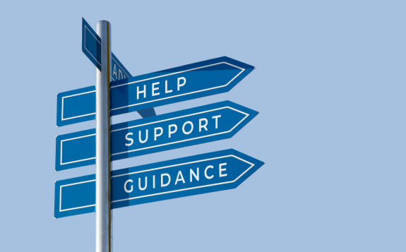 A signpost with three directional signs visible that read help, support, and guidance