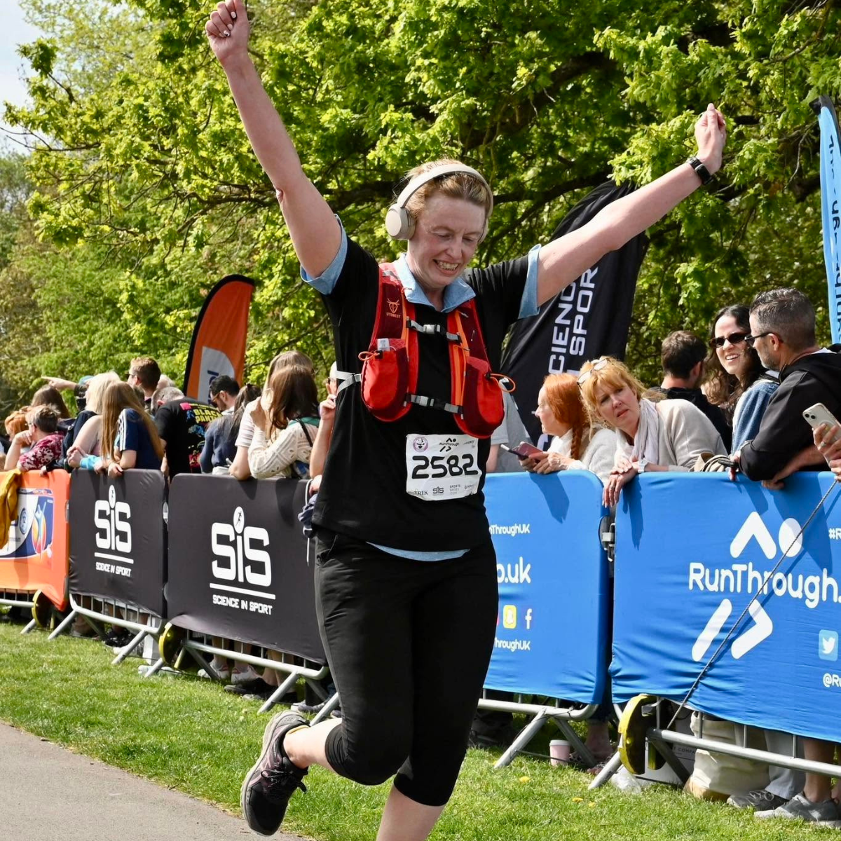 A runner crossing the finish line with their hands raised in the air.