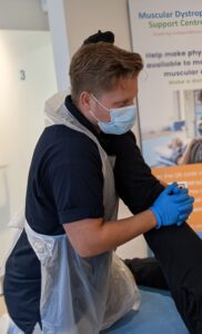 Close up of a physiotherapist performing a manual stretch on a patient. The Physiotherapist is wearing PPE.