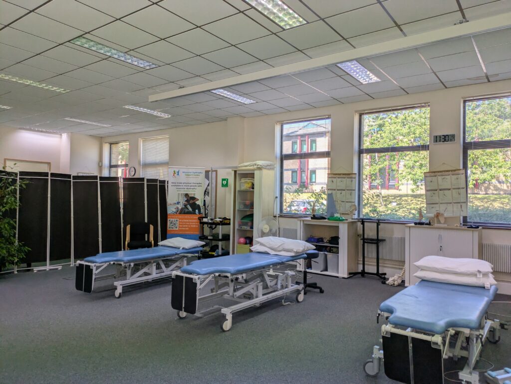 Treatment beds in the Coventry therapy area. Behind them is a MD Support Centre banner and privacy screens.