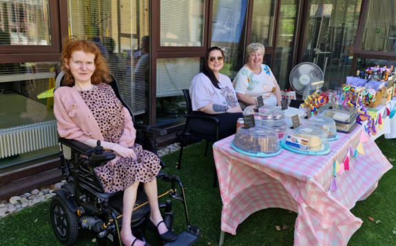 Events link tile A group of people sitting at a cake and tombola stall at a charity event.