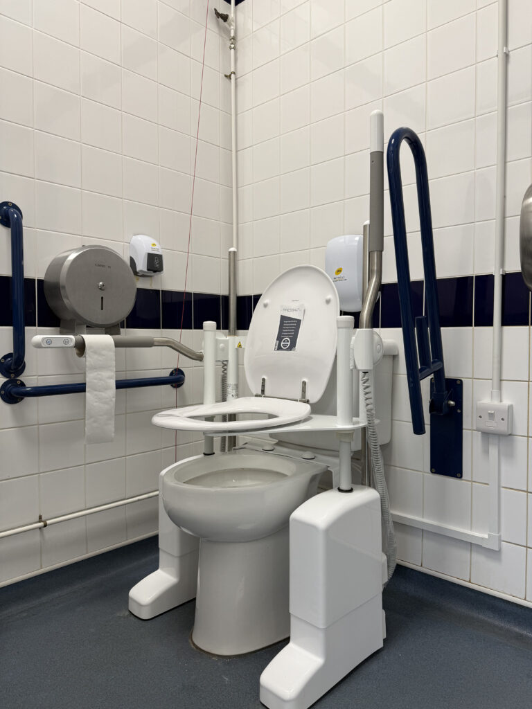 An accessible toilet with a rising seat lifted into an elevated position