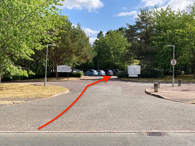 The entrance to a car park marked up with a red directional arrow